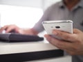 Man hands holding and working with mobile phone and computer