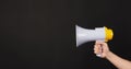 Man hands is holding yellow megaphone on black background