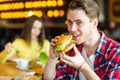 Man in hands holds a burger. Man eating a burger at the cafe