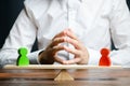 A man with hands in the lock and looks at the rival red and green figures on a scales. The concept of conflict resolution Royalty Free Stock Photo