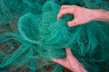 Man hands picking up a green fishing net