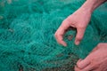 Man hands picking up a green fishing net. Waste in nature.