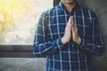 A man hands praying to God over concrete wall