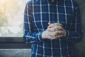 A man hands praying to God over concrete wall with window light