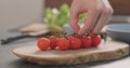 Man hands put cherry tomatoes branch on olive wood board Royalty Free Stock Photo