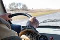 Man hands on the steering wheel of an old SUV . There are road ahead and steppe behind the windshield Royalty Free Stock Photo