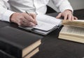 Man hands taking notes in planner. Businessman sitting at table with books or codes at home or in office and writing Royalty Free Stock Photo