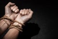 Man with hands tied with rope on black background. The concept of slavery or prisoner. Copy space for text. Royalty Free Stock Photo