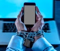 Man hands tied to mobile phone with chain padlock in internet or social media addiction Royalty Free Stock Photo