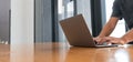 Man hands typing on the laptop keyboard on wooden desk in living room Royalty Free Stock Photo