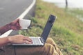 Man hands typing laptop notebook holding coffee cup outside office. Close up man hands using computer laptop sit on green park Royalty Free Stock Photo