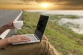 Man hands typing laptop notebook holding coffee cup outside office. Close up man hands using computer laptop sit on green park Royalty Free Stock Photo