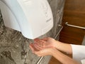 A man hands using automatic hand dryer in public toilet or restroom hygiene concept