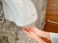 A man hands using automatic hand dryer in public toilet or restroom hygiene concept