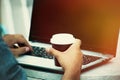 Man hands using laptop and holding cup of coffee outdoor closeup Royalty Free Stock Photo