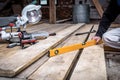 Man hands using yellow spirit level and measuring horizontal surface of wooden board for new floor Royalty Free Stock Photo