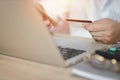 Man hands in white shirt sitting and holding credit card and using laptop computer on table for online payment or shopping online Royalty Free Stock Photo