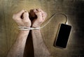 Man hands wrapped on wrists with mobile phone cable handcuffed in smart phone networking addiction concept Royalty Free Stock Photo