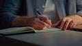 Man hands writing notebook at late office closeup. Anonymous guy making notes Royalty Free Stock Photo