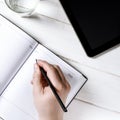 Man hands writing notes to the notebook on wooden table in home office Royalty Free Stock Photo