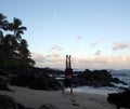 Man Handstanding on beach at dawn as wave crash on the North Shore