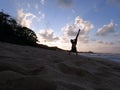 Man Handstanding on beach at sunset as wave crash