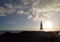 Man Handstanding on coastal rocks at sunset