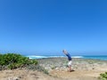 Man Handstanding on coral rocks on the beach as wave crash in th