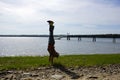 Man Handstands on rocky grassy beach with Pier Royalty Free Stock Photo