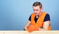 Man, handyman in working uniform and protective gloves handcrafting, light blue background. Carpenter concept. Carpenter Royalty Free Stock Photo