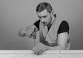 Man, handyman in working uniform and protective gloves handcrafting, light blue background. Carpenter, woodworker Royalty Free Stock Photo