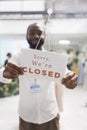 Man hanging closed sign in window of fashion boutique Royalty Free Stock Photo