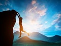 Man hanging on the edge of mountain at sunset