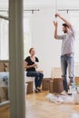 Man hanging a lamp while furnishing new home with his smiling wi Royalty Free Stock Photo