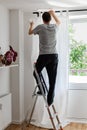 Man hangs white curtains on the curtain rod Royalty Free Stock Photo