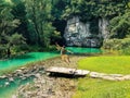 Man happily jumping on wooden planks on the side of a beautiful river