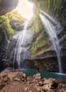 Man is happy on rocks in Madakaripura waterfall in tropical rainforest