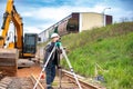 A man in a hard hat is capturing a picture of a busy construction site with various machinery and workers Royalty Free Stock Photo