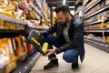 a man in a hardware store chooses a roller and a container for paint, construction and repair concept.