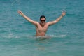 Man has fun in the blue sea by jumping up and spashing water. Royalty Free Stock Photo