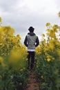 Man in the hat goes in rapeseed field Royalty Free Stock Photo