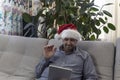 The man in the hat of Santa Claus wishes you a Happy New Year and Merry Christmas on your computer, tablet