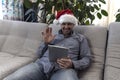 The man in the hat of Santa Claus wishes you a Happy New Year and Merry Christmas on your computer, tablet