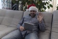 The man in the hat of Santa Claus wishes you a Happy New Year and Merry Christmas on your computer, tablet