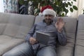 The man in the hat of Santa Claus wishes you a Happy New Year and Merry Christmas on your computer, tablet