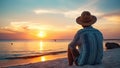 Man in hat sitting on the beach and watching the sunset over the sea Royalty Free Stock Photo