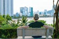 Man in hat is sitting on bench looking at beach with skyscrapers Royalty Free Stock Photo