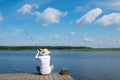 A man in a hat, sitting on the pier, throws a fishing rod, against the blue sky and the lake Royalty Free Stock Photo