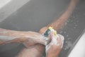 Man having a bath and using a scrubber sponge.