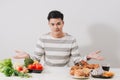 Man having hard choice between healthy and unhealthy food Royalty Free Stock Photo